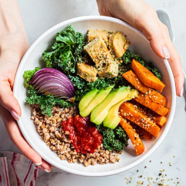 A healthy grain bowl with chicken, veggies, and avocado
